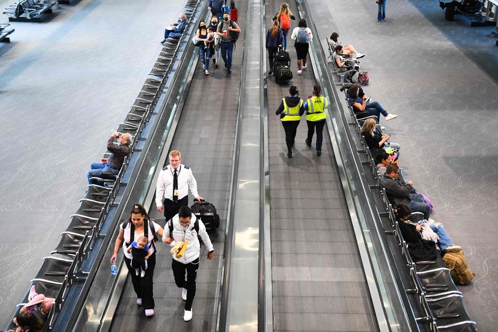 Sebagian penumpang dan kru pesawat tidak mengenakan masker saat berjalan di area terminal bandara di Denver, Colorado, AS, Selasa (19/4/2022). Pengadilan Federal AS menyatakan kewajiban mengenakan masker di sarana-sarana transportasi umum tidak berlaku lagi.