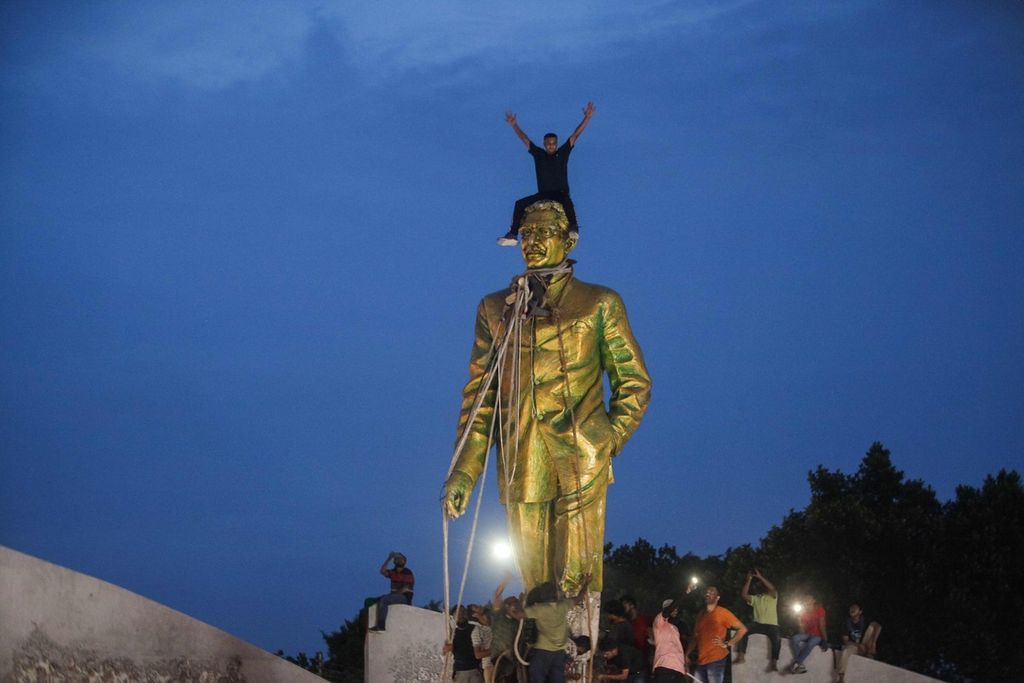 Pengunjuk rasa berkumpul di sekitar patung Bapak Bangsa Bangladesh Sheikh Mujibur Rahman di Dhaka, Bangladesh, Senin (5/8/2024).