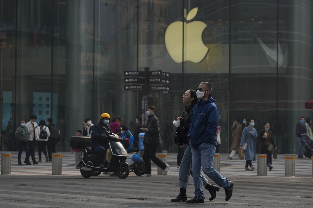 Warga yang memakai masker berjalan di depan salah satu toko Apple di kawasan perbelanjaan di Beijing, China, 5 Maret 2023. 