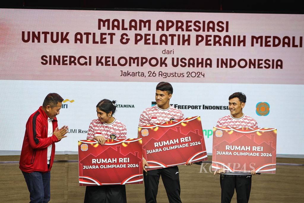 Ketua Umum Real Estat Indonesia Joko Suranto (kiri) memberikan hadiah satu unit rumah kepada tiga atlet peraih medali Olimpiade Paris 2024, yakni Gregoria Mariska Tunjung (bulu tangkis), Rizki Juniansyah (angkat besi), dan Veddriq Leonardo (panjat tebing) di Jakarta, Senin (26/8/2024). 