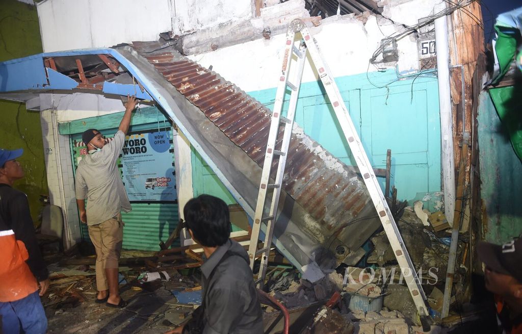 Petugas mengecek bagian yang rusak sebuah bangunan di Jalan Ngaglik pascagempa di Surabaya, Jumat (22/3/2024). Gempa yang terjadi beberapa kali tersebut berpusat di laut dengan jarak 130 kilometer timur laut Tuban.