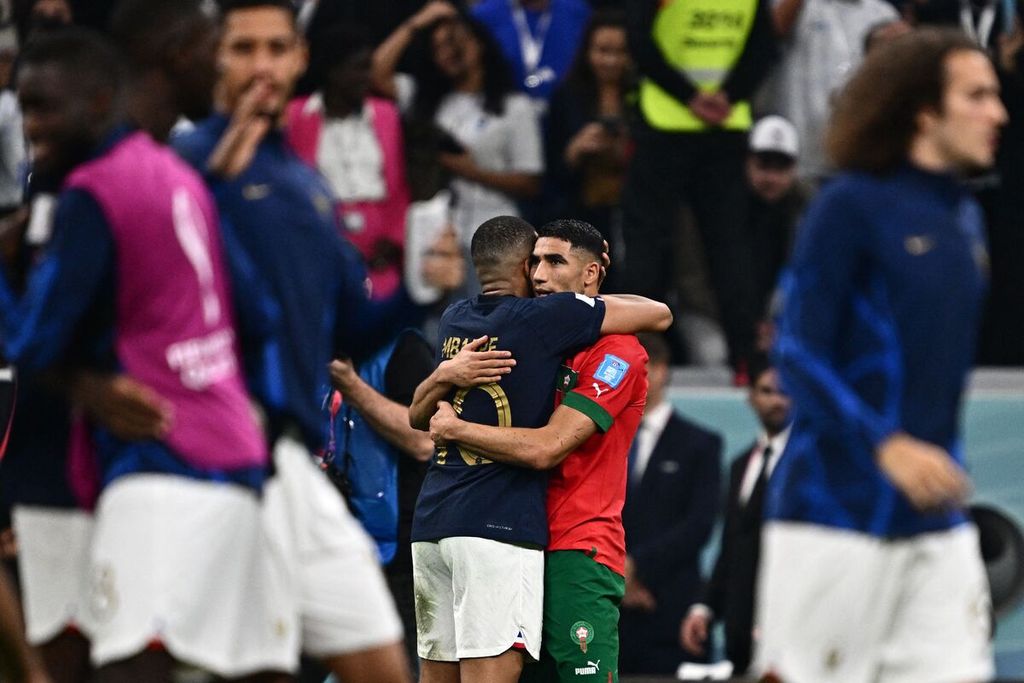 Penyerang Perancis, Kylian Mbappe (kiri tengah), memeluk sahabatnya, bek sayap Maroko, Achraf Hakimi, seusai berakhirnya laga semifinal Piala Dunia 2022 di Stadion Al-Bayt, Al Khor, Qatar, Kamis (15/12/2022) dini hari WIB. Laga itu dimenangi Perancis, 2-0.