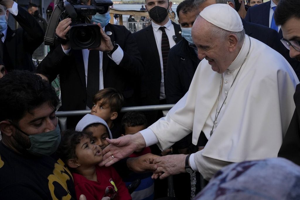 Paus Fransiskus berinteraksi dengan anak-anak pengungsi dan pencari suaka saat mengunjungi kamp pengungsi Karatepe di Pulau Lesbos, Yunani, Minggu (5/12/2021). 