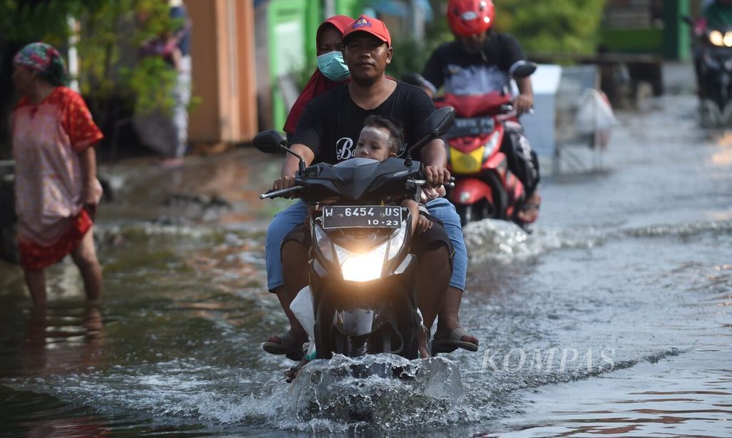Warga melintasi banjir di Desa Kedung Banteng, Kecamatan Tanggulangin, Kabupaten Sidoarjo, Jawa Timur, Kamis (6/2/2020). 