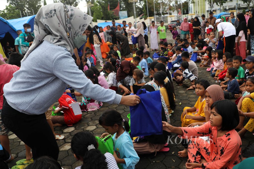 Petugas membagikan paket alat tulis dan gambar kepada anak-anak di kompleks kantor Bupati Pasaman Barat, Kabupaten Pasaman Barat, Sumatera Barat, Selasa (1/3/2022). Kegiatan menulis dan menggambar bersama ini sebagai bagian dari <i>trauma healing</i>.