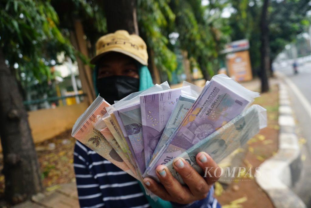 Alam Siahaan menunjukkan kantong-kantong plastik berisi pecahan uang kertas Rp 2.000, Rp 5.000, dan Rp 10.000 di tepi jalan di daerah Pondok Indah, Jakarta Selatan, Selasa (18/4/2023). Hampir semua penjaja jasa penukaran uang tersebut adalah perantau Batak dari Sumatera Utara.