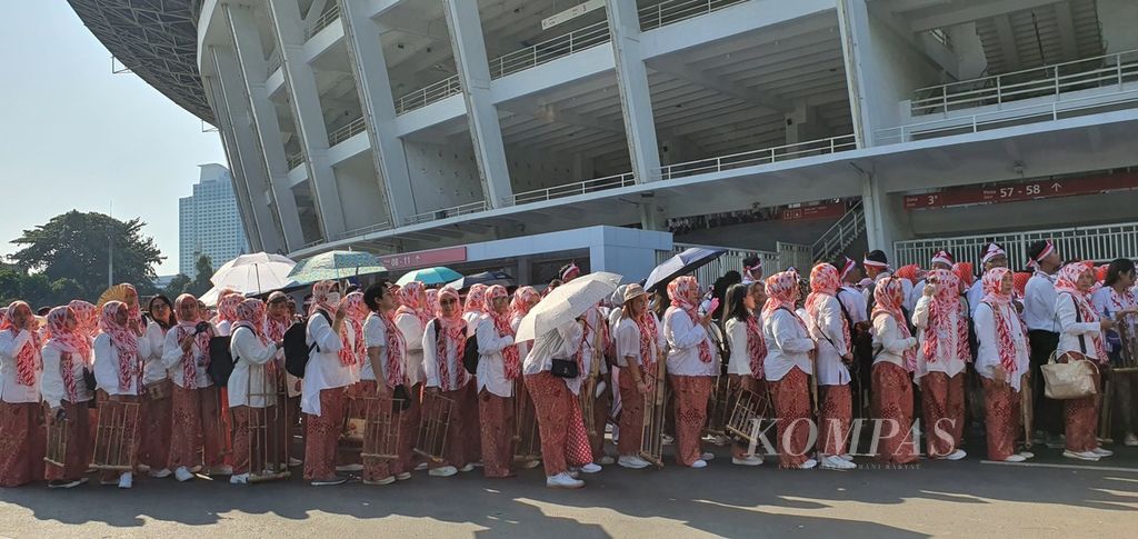 Para peserta pergelaran angklung terbesar di dunia mengantre ke Stadion Utama Gelora Bung Karno, Jakarta, Sabtu (5/8/2023) siang. Kendati terik, mereka tetap bersiap untuk bermain angklung dalam ensambel yang terdiri atas lebih dari 15.000 orang.