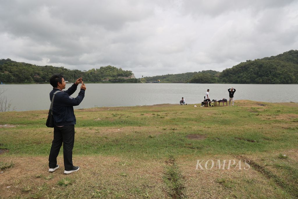 Wisatawan menikmati suasana di tepi Waduk Sermo di Desa Hargowilis, Kokap, Kulon Progo, DI Yogyakarta, Kamis (5/1/2023). 