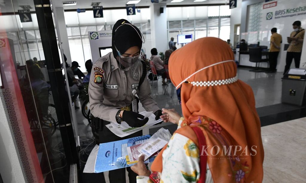 Petugas memberikan tiket nomor urut antrean kepada warga yang akan mengurus administrasi BPJS Kesehatan di Kantor Cabang BPJS Kesehatan Jakarta Selatan, Jakarta, akhir November 2021. 