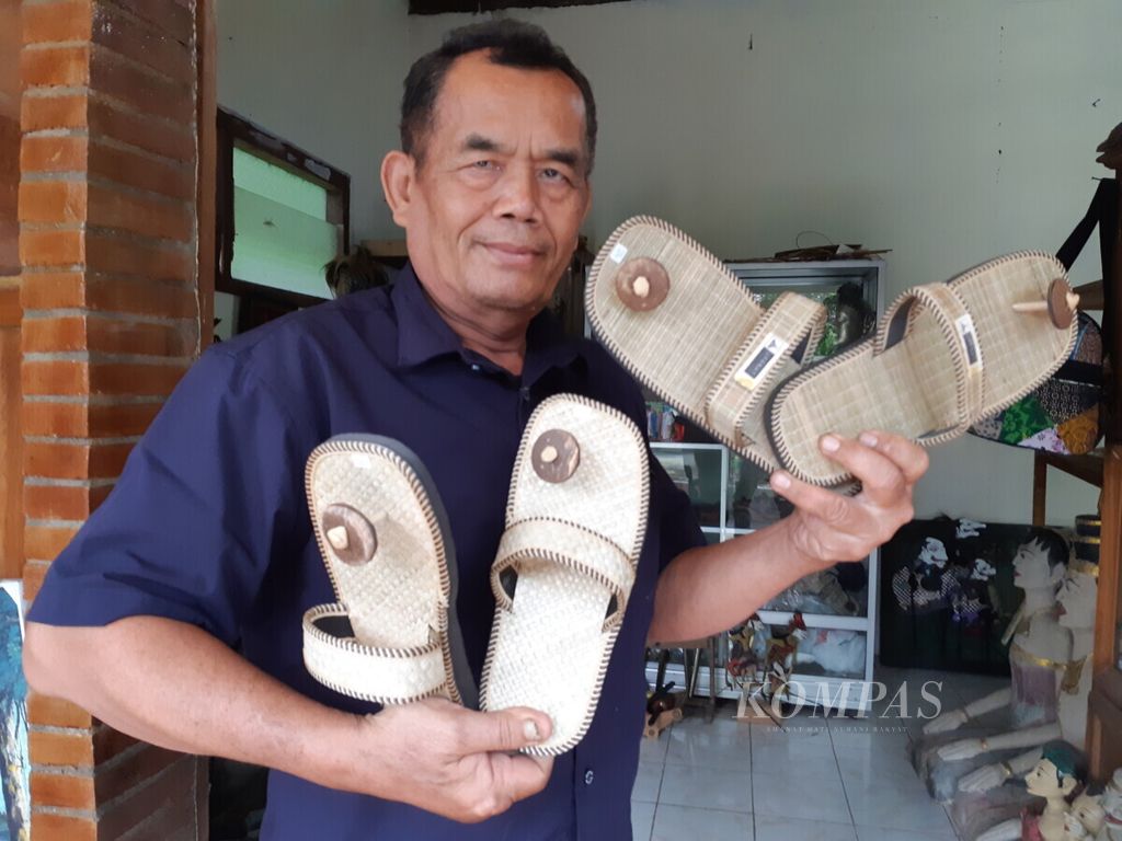 Pemilik usaha kerajinan BW Craft Borobudur, Basiyo, menunjukkan sandal buatannya, Jumat (12/11/2021), di rumahnya yang berlokasi di Desa Borobudur, Kecamatan Borobudur, Kabupaten Magelang, Jawa Tengah. Sandal buatan Basiyo itu merupakan sandal khusus yang menurut rencana bakal diwajibkan dipakai oleh pengunjung yang ingin naik ke Candi Borobudur. 