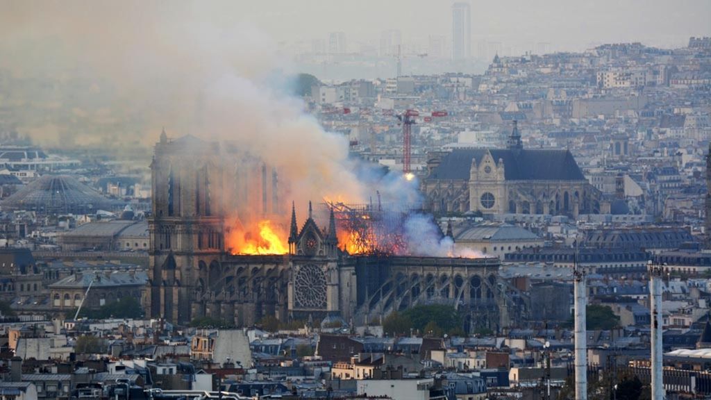 Asap dan api terlihat saat terjadi kebakaran di Katedral Notre-Dame di Paris, Perancis, Senin (15/4/2019). Api dan asap merayap dari puncak menara dan atap katedral gotik yang dikunjungi jutaan orang dalam satu tahun itu. Saat kebakaran terjadi, katedral tersebut sedang direnovasi.