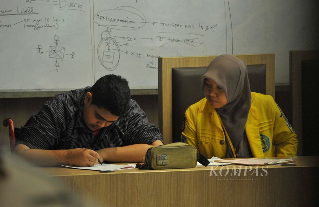 Dengan dibantu pendamping mahasiswa, penyandang tunadaksa Ibrahim (kiri), mengerjakan soal ujian seleksi bersama masuk perguruan tinggi negeri (SBMPTN) di Gedung C Fakultas Hukum Universitas Indonesia, Depok, Selasa (18/6/2013) lalu. Ujian SBMPTN panitia lokal Jakarta diikuti 44.165 peserta yang terdiri dari 17.713 peserta ujian IPA, 22.755 peserta ujian IPS, dan 3.697 peserta ujian campuran.