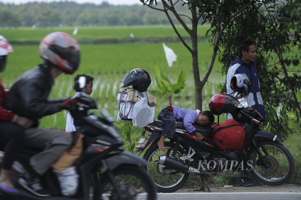 Fahrul (5) tertidur nyenyak di atas jok motor ketika istrirahat dalam perjalanan mudik bersama orangtuanya ke Tegal di jalur pantai utara, Kecamatan Sukra, Kabupaten Indramayu, Jawa Barat, Senin (4/6/2016).