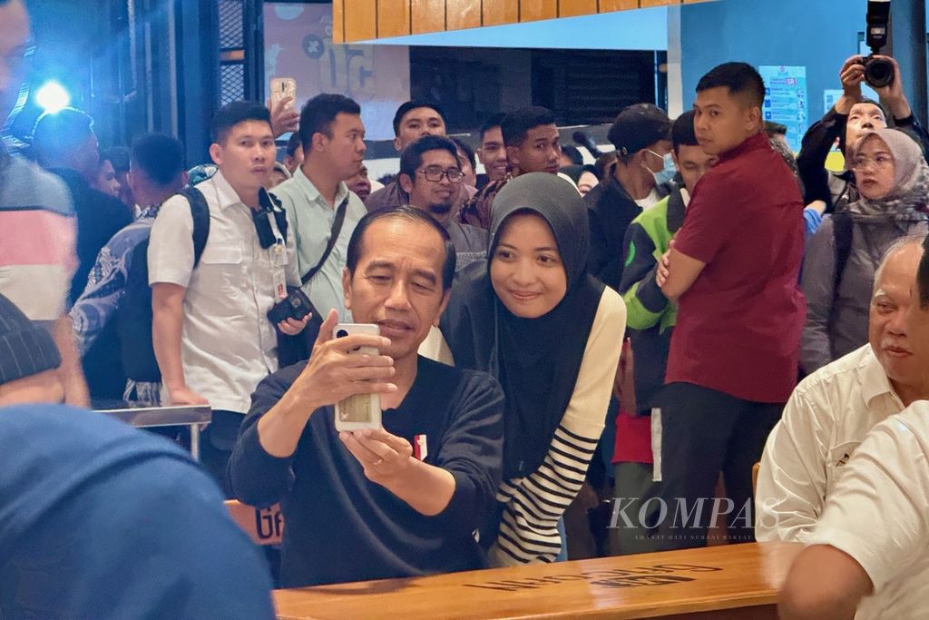Presiden Joko Widodo melayani foto bersama dengan salah seorang pengunjung di kedai Mie Gacoan di Kota Mataram, Nusa Tenggara Barat, Selasa (30/4/2024) malam. Presiden berada di Lombok dalam rangka kunjungan kerja di Nusa Tenggara Barat.