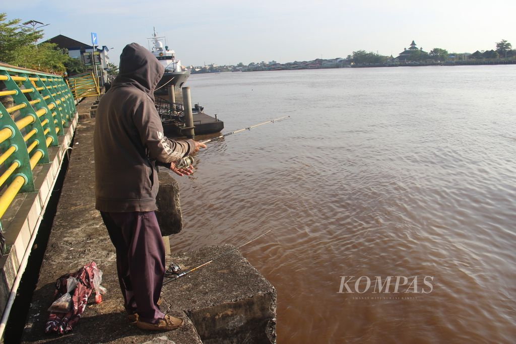 Warga memancing di tepian Sungai Kapuas, Kota Pontianak, Kalimantan Barat, Minggu (14/7/2024).