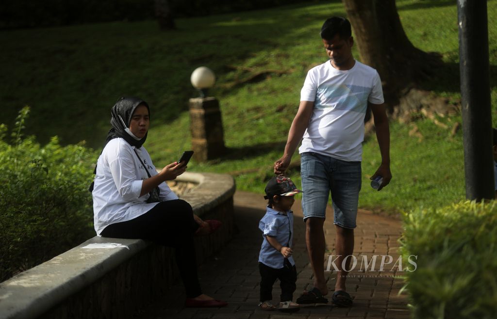 Warga berjalan dengan anaknya di trek pedestrian di pinggir kolam di kawasan Taman Ayodya, Kebayoran Baru, Jakarta Selatan, Minggu (1/1/2023). Taman ini juga menjadi pilihan wisata keluarga. 