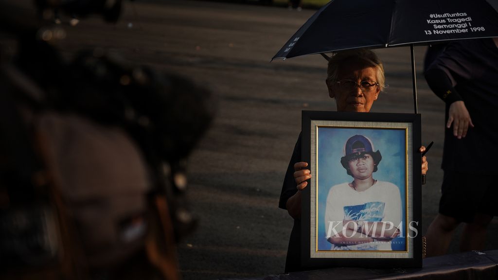 Aktivis Aksi Kamisan, Maria Catarina Sumarsih, memegang foto anaknya, Realino Norma Irmawan atau Wawan, yang menjadi korban Peristiwa Semanggi I saat Aksi Kamisan di seberang Istana Merdeka, Jakarta, Kamis (22/6/2023).