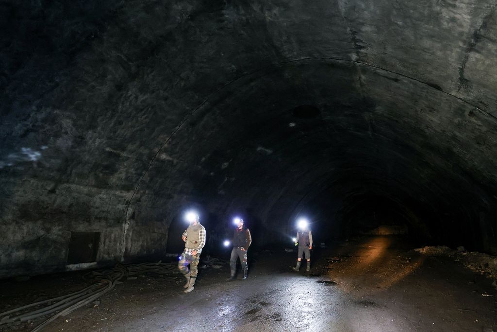 Pengunjung menyalakan senter saat berjalan di dalam terowongan gelap di pangkalan udara tentara bawah tanah Zeljava di jantung gunung Pljesevica, di perbatasan Kroasia dengan Bosnia, Rabu (4/10/2023). 