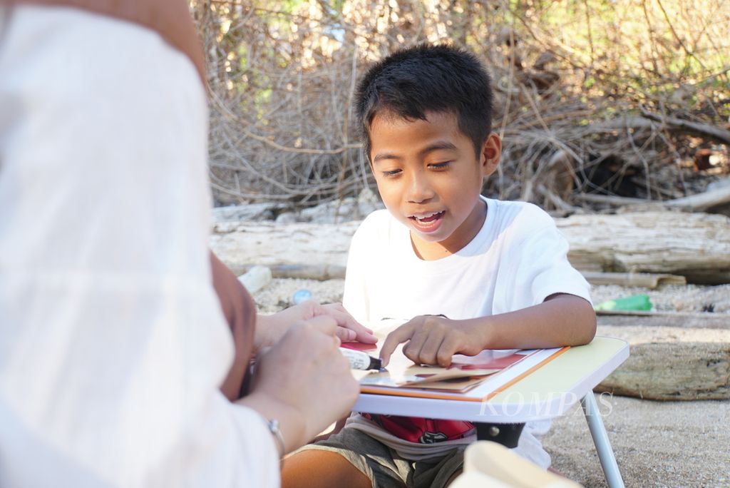 Al Ghazali (9) perlahan membaca buku anak-anak, Sabtu (18/11/2023), di Pulau Bunaken, Manado, Sulawesi Utara. 