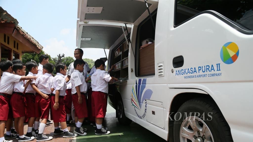 Murid-murid SDN Setu 1 Jakarta Timur memanfaatkan perpustakaan keliling untuk membaca buku bacaan, seperti komik dan novel, di sekolah mereka, Selasa (26/2/2019). Berdasarkan data Jendela Pendidikan dan Kebudayaan Kemendikbud 2018, baru 55 persen dari total 149.000 SD yang punya perpustakaan sekolah. 