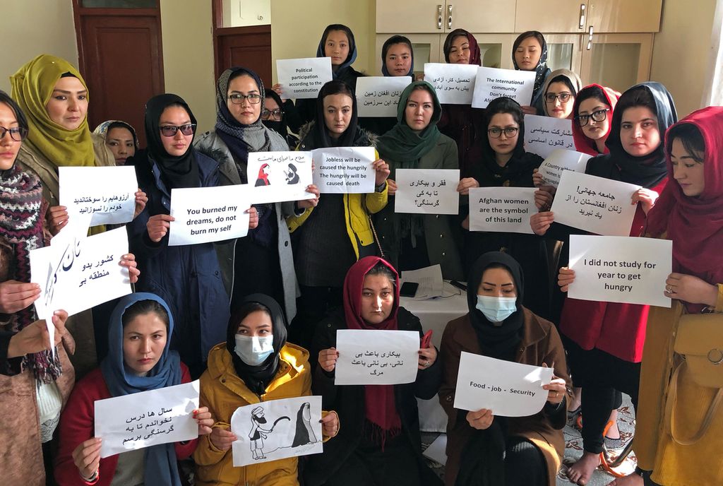 Foto yang diambil pada 27 Desember 2021 memperlihatkan sejumlah perempuan Afghanistan memegang kertas bertuliskan protes terhadap pengekangan dan pembatasan kegiatan perempuan oleh kelompok Taliban yang berkuasa. Satu tahun kemudian, 21 Desember 2022, Taliban melarang gadis Afghanistan untuk mengecap pendidikan tinggi. 