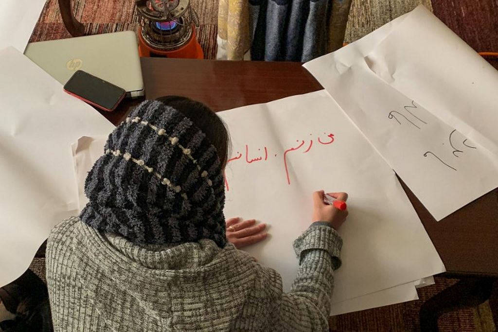 Dalam gambar yang diambil pada 15 Januari 2022 ini seorang perempuan Afghanistan menulis poster menjelang aksi protes kaumnya menuntut penegakan hak-hak perempuan, di Kabul. Perempuan menyuarakan kepentingannya dengan goresan-goresan pena untuk dibaca oleh masyarakat luar, terutama komunitas internasional tentang kembalinya rezim keras Taliban. 