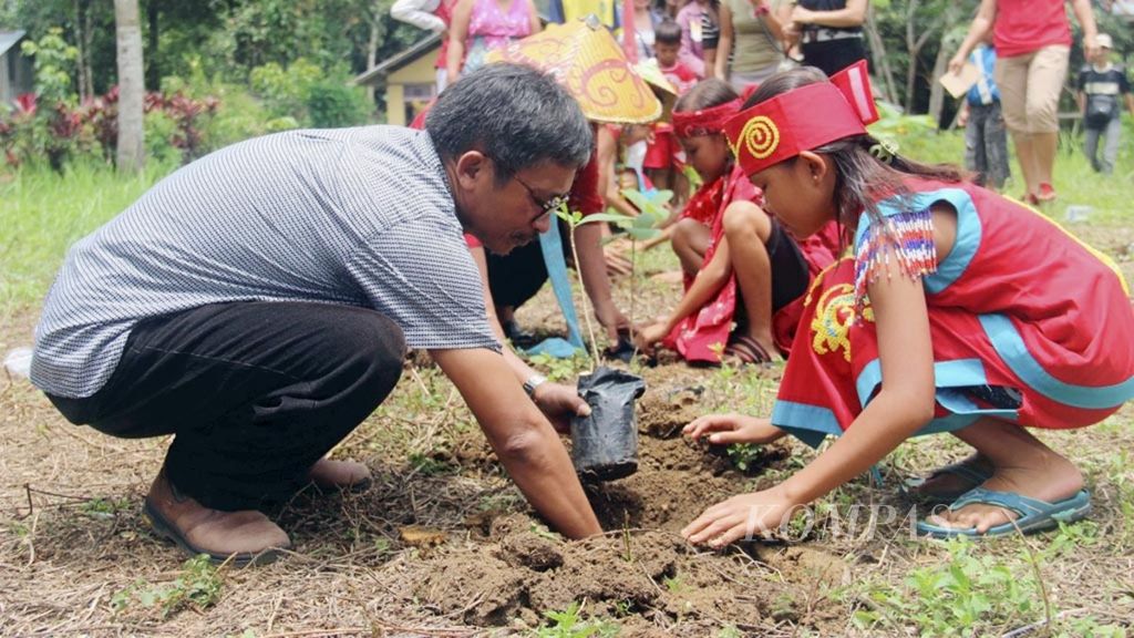 Sekretaris Jenderal Aliansi Masyarakat Adat Nusantara Abdon Nababan (mengenakan kemeja) bersama siswi Sekolah Adat Samabue di Kecamatan Menjalin, Kabupaten Landak, Kalimantan Barat, menanam pohon pada 25 Februari 2017.