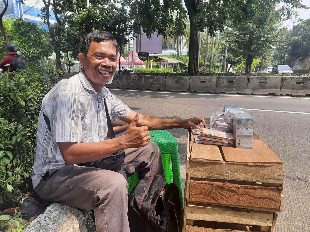 Penjual jasa penukaran uang, Lambok Sitoru (55) sedang menanti pelanggan di Jalan Teuku Nyak Arief, Jakarta Selatan, Rabu (19/4/2023).