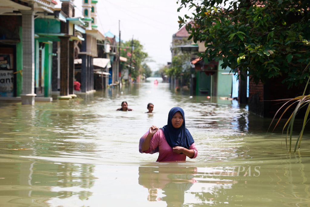 Warga melintasi banjir yang merendam permukiman mereka di Desa Wonoketingal, Kecamatan Karanganyar, Kabupaten Demak, Jawa Tengah, Selasa (19/3/2024). 