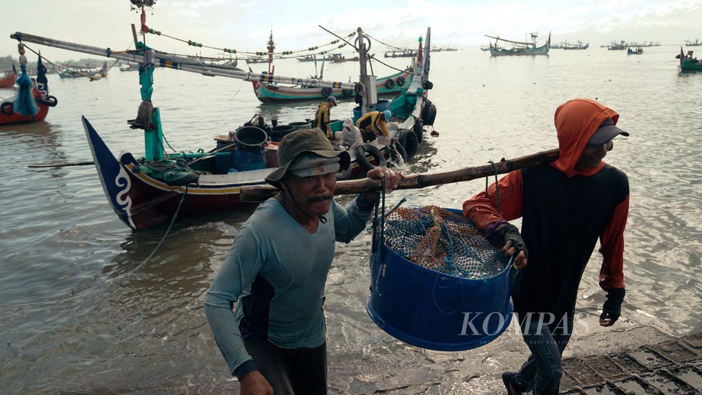 Nelayan mengangkut hasil laut yang sudah diberi bongkahan es batu di Tempat Pelelangan Ikan (TPI) Brak Kalimoro di Kecamatan Muncar, Banyuwangi, Jawa Timur, Selasa (31/5/2022). Nelayan kecil kian terdesak kapal ikan berukuran besar. Kuota tangkapan ikan yang akan diberikan kepada nelayan lokal di zona industri perikanan diproyeksikan 2,8 juta ton per tahun. 