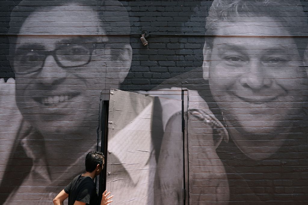 Foto yang diambil pada 20 Juli 2022 memperlihatkan seseorang membuka pintu yang menjadi bagian dari sebuah mural dan berisi foto wajah Siamak Namazi (kiri, berkacamata), warga Amerika Serikat yang ditahan Iran, di sudut kota Washington DC, AS.  