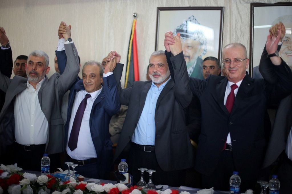 Perdana Menteri Palestina Rami Hamdallah (kanan) dan pemimpin Hamas, Ismail Haniyeh, mengangkat tangan dalam pertemuan di Gaza, Senin (2/10/2017).