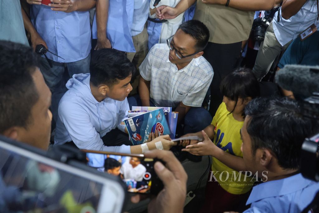 Calon wakil presiden nomor urut 2, Gibran Rakabuming Raka, membagikan buku kepada anak-anak di Jalan Rawa Bebek 1, Penjaringan, Jakarta Utara, Jumat (1/12/2023). 