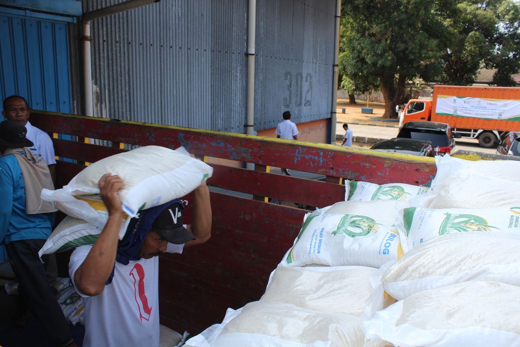 Pekerja mengangkut karung berisi beras dari gudang menuju truk di Gudang Bulog Tuk di Jalan Brigadir Jenderal Dharsono, Cirebon, Jawa Barat, Selasa (19/9/2023). 