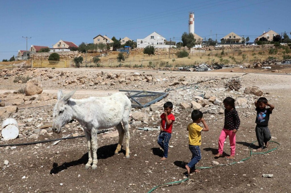 Anak-anak Palestina bermain di dekat keledai di desa Um al-Kheir di “area C”, di depan permukiman Yahudi di Ma’on, dekat kota Hebron di Tepi Barat, pada 14 Juni 2020. 