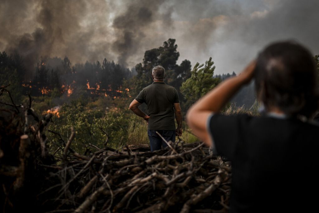 Warga lokal menyaksikan kebakaran hutan di Orjais, Covilha di Portugal tengah, Selasa (16/8/2022). 