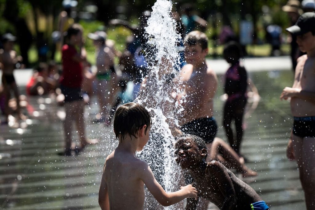 Anak-anak di Nantes, Perancis, mendinginkan badan di air mancur taman di tengah cuaca musim panas yang terik, 13 Juli 2022. 