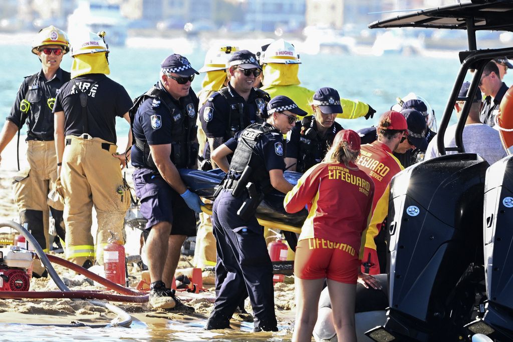 Petugas bantuan darurat mengeluarkan tubuh korban dari helikopter yang bertabrakan dengan helikopter lainnya di dekat Seaworld, Gold Coast, Australia, Senin (2/1/2023). 