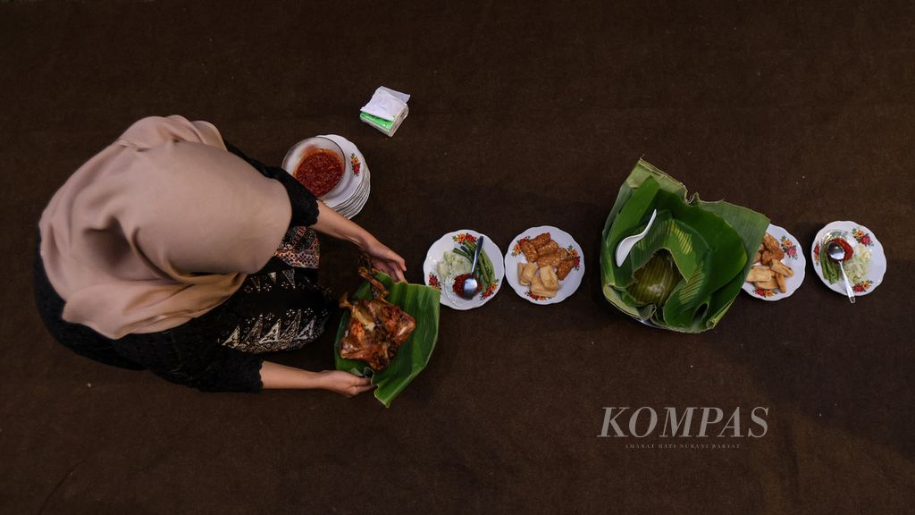 Seorang perempuan menata pecel<i> pithik</i> untuk didoakan sebelum disantap dalam acara selamatan di  Desa Kemiren, Kabupaten Banyuwangi, Jawa Timur, Jumat (17/11/2023). Bagi mayoritas warga Desa Kemiren, makanan merupakan bagian dari ritual untuk menghormati para leluhur mereka. 