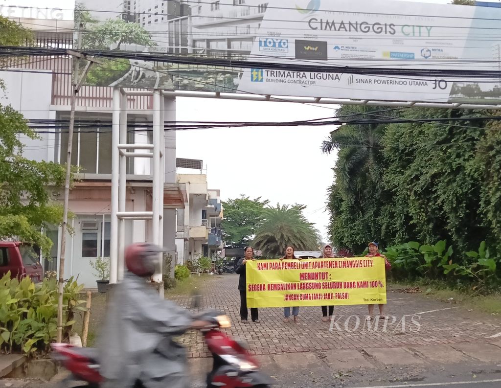 Para korban di depan gerbang Cimanggis City, Kota Depok, Jawa Barat, 16 Desember 2022, sembari membentangkan spanduk protes dan tuntutan kepada pihak pengembang agar mengembalikan uang yang sudah mereka bayarkan.