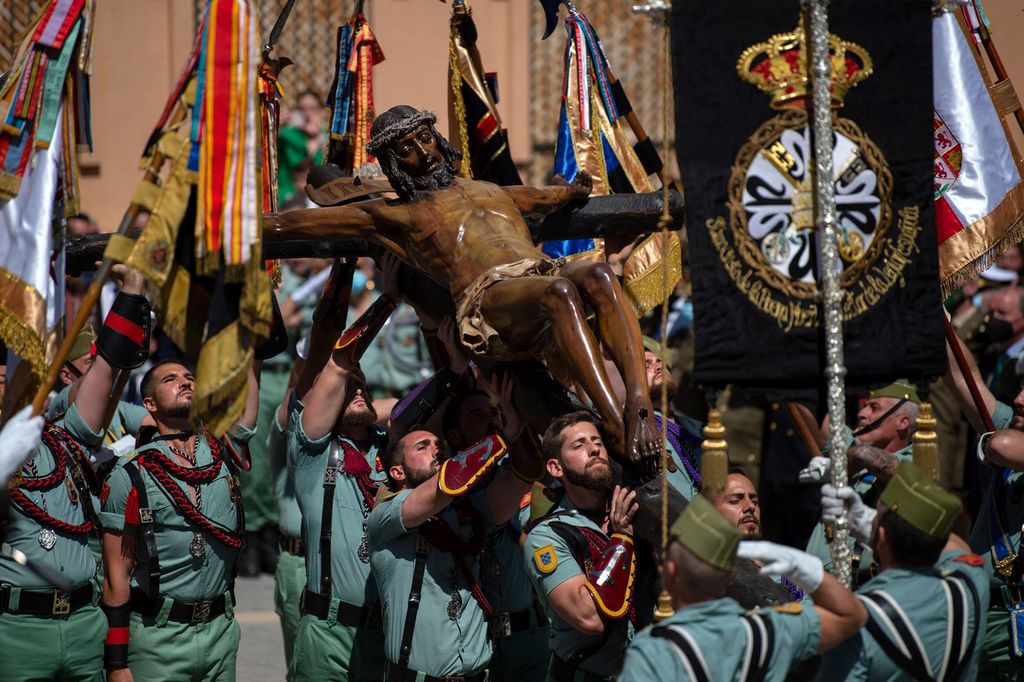 Spanish legionnaires bear a crucifix figure depicting 'El Cristo de la Buena Muerte' (Christ of the Good Death) during the 'Cristo de Mena' Holy Week procession on April 14, 2022 in Malaga, southern Spain. - Christian believers around the world mark the Holy Week of Easter in celebration of the crucifixion and resurrection of Jesus Christ.