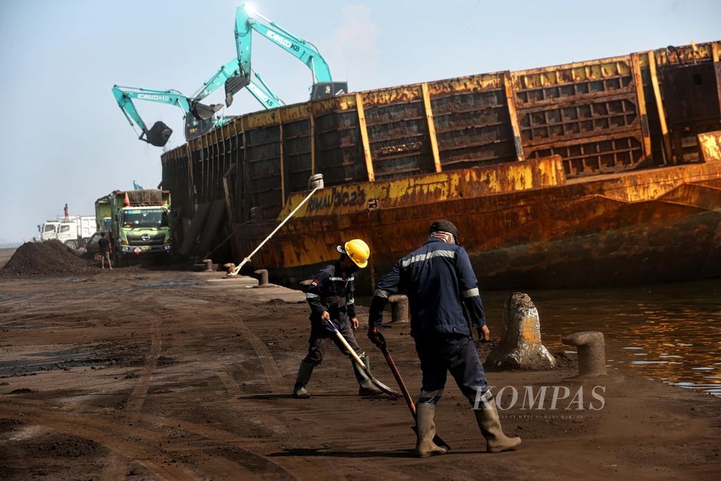 Pekerja membersihkan ceceran batubara di Pelabuhan KCN Marunda, Jakarta Utara, selesai bongkar muat agar tidak berdebu, awal Januari 2022. 