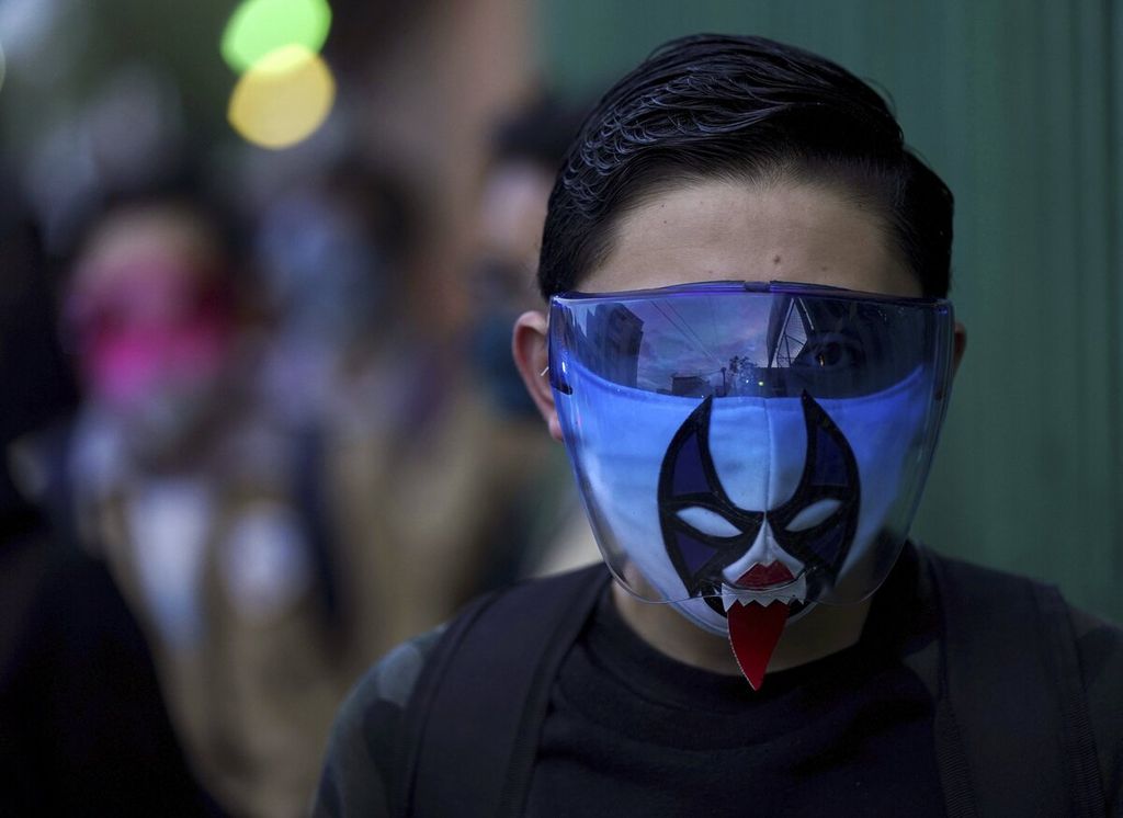 Seorang siswa yang memakai masker dan topeng gulat Lucha Libre berjalan memasuki sekolah untuk mengikuti hari pertama kelas tatap muka di Mexico City, Meksiko, Senin (30/8/2021). 