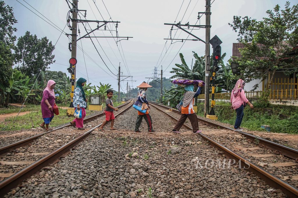 Warga menyeberangi jalur kereta api di sebuah pelintasan sebidang yang tak dijaga di kawasan Cibogo, Tangerang, Banten, Senin (15/3/2021). Pelintasan itu adalah akses tercepat warga Cibogo menuju kawasan BSD.
