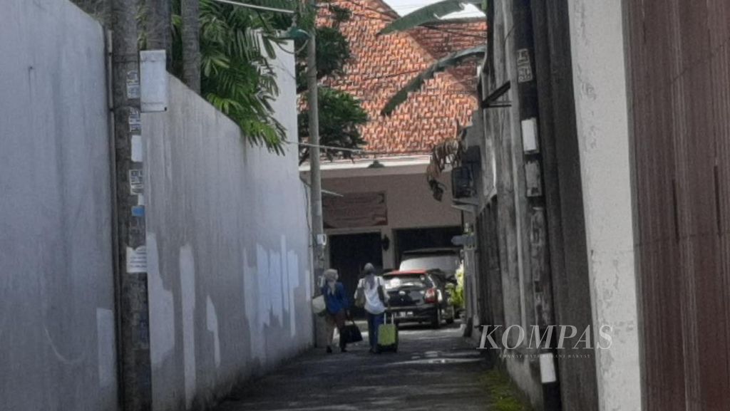 Dua tamu hotel di Kampung Prawiotaman, Yogyakarta, yang baru saja <i>check out</i>, membawa <i>travel bag</i> keluar dari gang, sembari menunggu kendaraan yang akan mengangkut mereka untuk kembali pulang, Sabtu (6/5/2022).