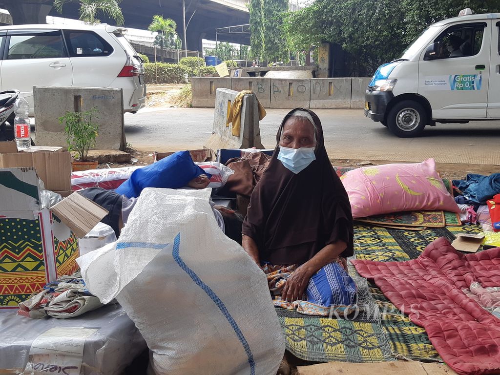 Asiti (78) duduk beralaskan tikar sembari menjaga cucunya yang terlelap di tepi Jalan Basuki Rachmat, Cipinang Besar, Jakarta Timur, Senin (2/5/2022).
