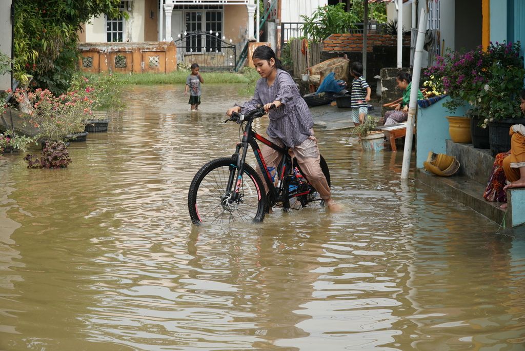 Anak-anak bermain sepeda di jalan yang digenangi banjir di Perumahan Pondok Pratama 3, Kelurahan Lubuk Buaya, Kecamatan Koto Tangah, Padang, Sumatera Barat, Kamis (19/8/2021) pagi. Banjir merendam sejumlah titik permukiman Kota Padang, Rabu (18/8/2021) malam, dipicu hujan deras sejak sore.