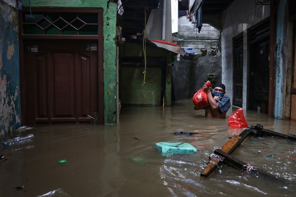 Seorang warga mengevakuasi barang dari rumah saat banjir di Kampung Melayu, Jatinegara, Jakarta Timur, Senin (27/2/2023). 