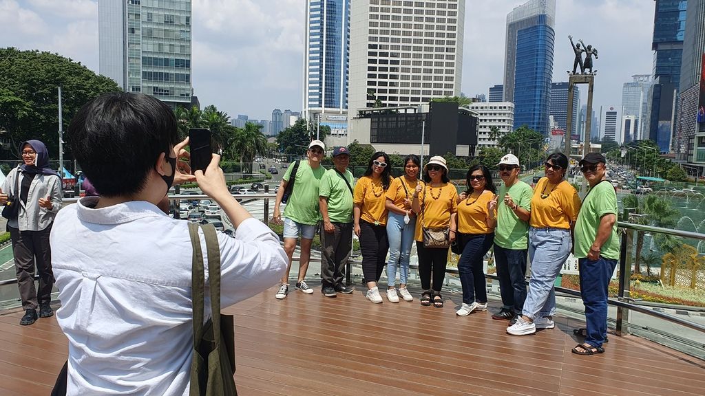 Caesar Dwi (paling kiri) berfoto bersama keluarga besarnya di anjungan halte di Halte TransJakarta, Bundaran HI, Jakarta, Minggu (23/4/2023). Halte berdesain kapal pesiar menjadi magnet baru bagi masyrakat untuk menikmati Ibu Kota yang sepi pada hari kedua Lebaran 2023.