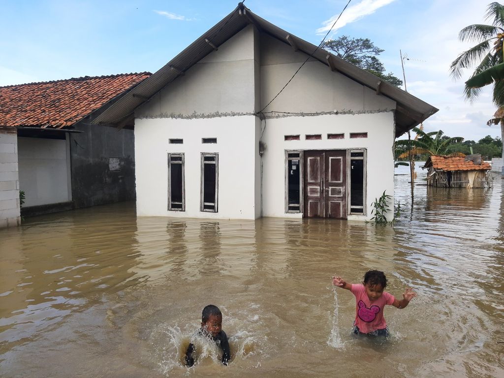 Anak-anak bermain di air genangan depan rumah di Desa Pantai Harapan Jaya, Kecamatan Muara Gembong, Kabupaten Bekasi, Jumat (3/3/2023). Ketinggian air mulai 50 sentimeter.